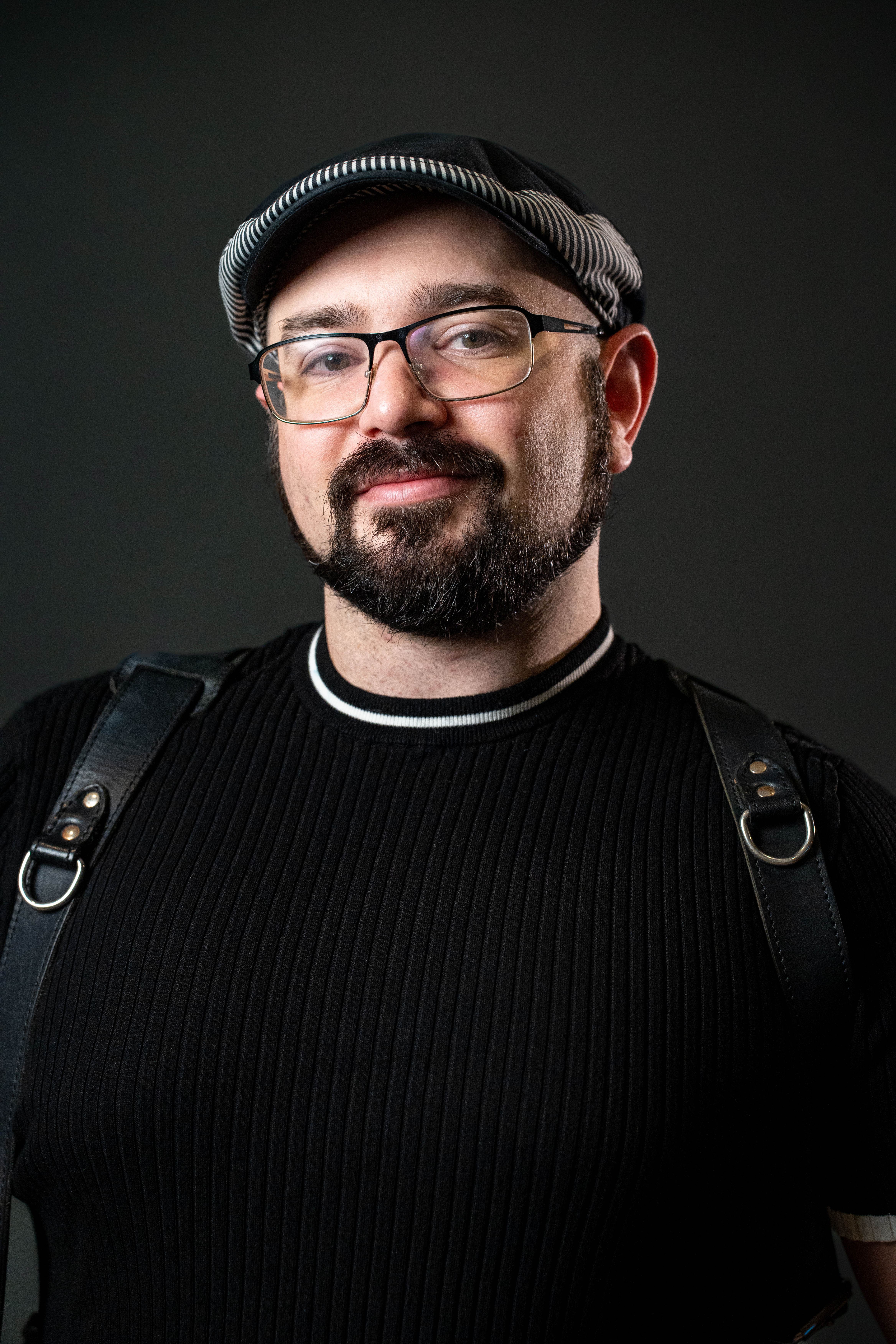 Professional headshot — man with flat cap on studio background